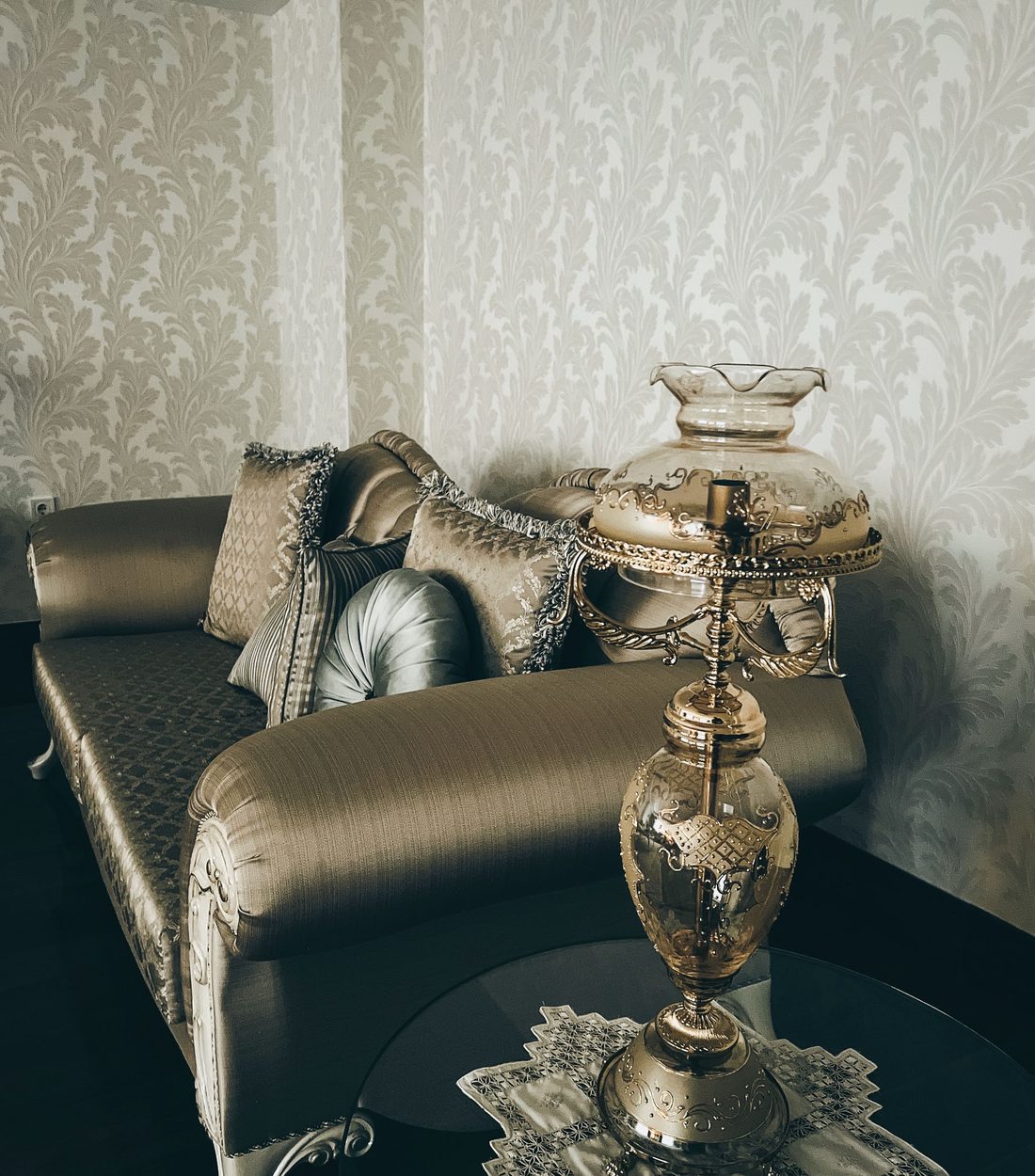 Moody luxe corner with silver damask wallpaper and a glass lamp